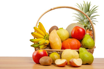 Composition with assorted fruits in wicker basket on wooden table, copy space