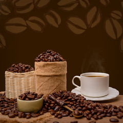 Hot cup of coffee  and beans with burlap sack on the wooden table, with copy space