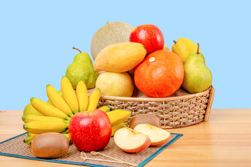 Composition with assorted fruits in wicker basket on wooden table, copy space