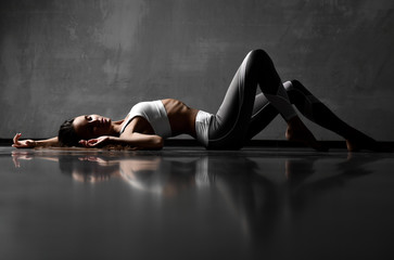 Sport woman posing lying on floor in elastic sport cloth with closed eyes 