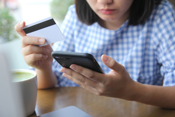 Young woman hands holding credit card and using laptop smart phone online shopping