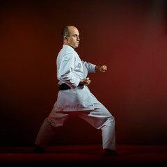 On a dark background, a black belt athlete performs formal karate exercises