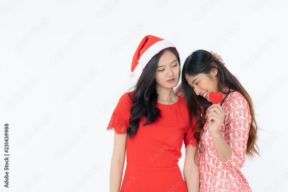 Wall mural Photo of asian curious woman in red dress rejoicing her birthday or new year. Young two woman holding red heart being excited and surprised  holiday present isolated white background