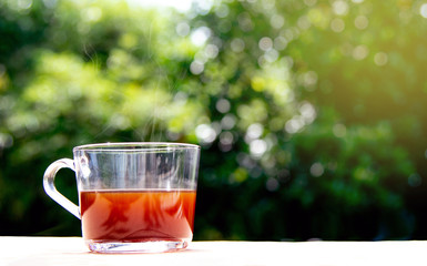 cup of hot coffee with green leaves blurred background