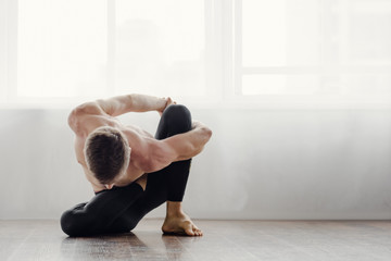Fototapeta na wymiar Athletic muscular young man practicing yoga in studio