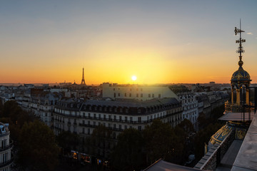 Naklejka premium Yellow vivid sunset on Paris roof of ancient stone Victorian buildings with the Eiffel Tower not lit yet, France