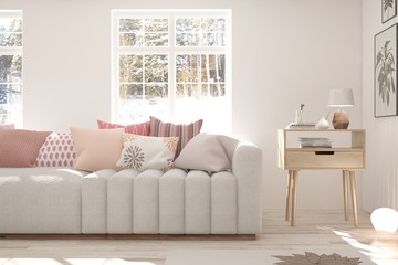 Obraz premium White room with sofa and winter landscape in window. Scandinavian interior design. 3D illustration