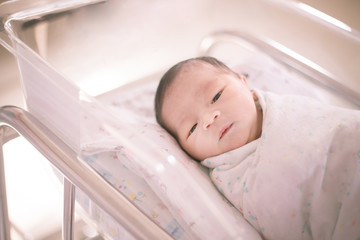 New born baby after birth  lying on a bed in nursery in the hospital.