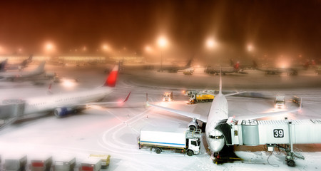 winter wonderland airport overview at night with snow aircraft apron passenger planes parked to...