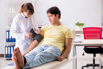 Fototapeta premium Young doctor checking patients blood pressure