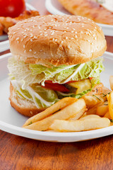 burger with vegetables and fried potatoes on white plate close-up in fast food cafe
