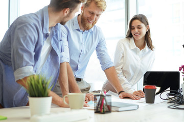 Young confident business people discussing something while looking at blueprint in the office, architecture team.