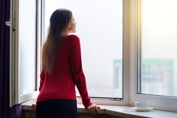 Young woman opened a window enjoying the fresh air, side view
