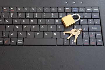 Golden locked padlock and keys on black computer laptop or tablet keyboard. Concept of internet password security, data privacy, cybercrime prevention. Selective focus.