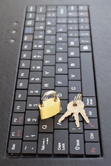 Golden locked padlock and keys on black computer laptop or tablet keyboard. Concept of internet password security, data privacy, cybercrime prevention. Selective focus.