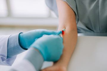 Fototapeta premium Close up Hand of nurse, doctor or Medical technologist in blue gloves taking blood sample from a patient in the hospital.