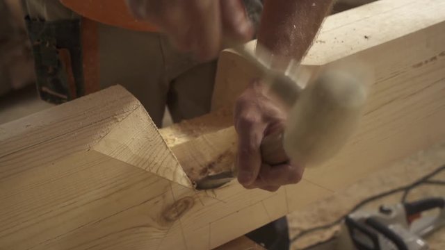 slow motion chisel in the hands of the master, he hits the mallet. shavings take off, a piece of wood breaks off. Close-up manufacturing of timber according to Norwegian technology