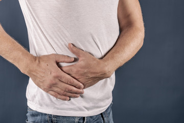 Man suffering from pain in his side. Blue background. Stomach, liver pain, pancreas, kidneys