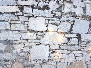Ancient medieval stone masonry. Texture of a fragment of a wall of an old structure. A background for design and creative work. Decoration and exterior decoration of the building. Construction works.