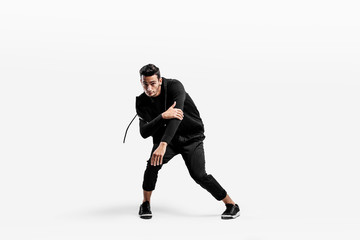 Handsome young dancer wearing a black sweatshirt and black pants is dancing breakdance