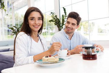 Loving couple sitting in cafe eat desserts and drinking tea.