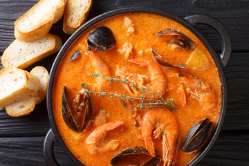 Catalan authentic spicy Suquet de Peix soup with potatoes, shrimps, mussels, herbs and fish with picad close-up. Horizontal top view