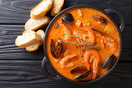 Seafood spicy soup with potatoes, shrimps, mussels, herbs and fish from a picad closeup served with toast. Horizontal top view