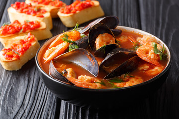 Traditional recipe for French bouillabaisse soup with seafood and fish close-up in a bowl served with toasts. horizontal - obrazy, fototapety, plakaty