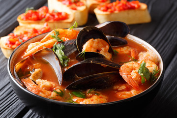 French seafood bouillabaisse soup closeup in a bowl served with toast. horizontal