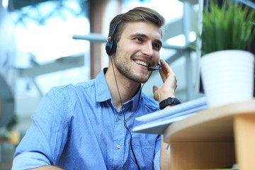 Smiling friendly handsome young male call centre operator.