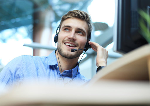 Smiling friendly handsome young male call centre operator.