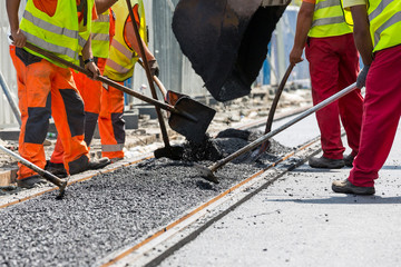 Workers construct asphalt road and railroad lines - obrazy, fototapety, plakaty