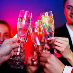 Close view of clinking glasses of sparkling champagne, big company of friends on the christmas or new year perty is celebrating together