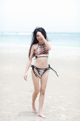 Portrait of pretty beautiful sport fashion woman in  bikini posing in summer near the sea and blue sky in sunshine with gorgeous smile in happy mood on tropic island on vacation