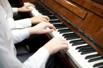 Fototapeta na wymiar Children play piano in four hands