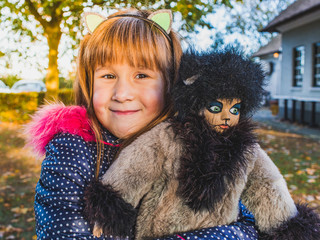 Cute little girl playing with her favorite doll-puss outdoor.Autumn break at school.