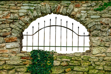 An old stone wall with a metal grille on the opening.