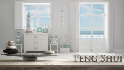 Wooden vintage table shelf with stone balance and 3d letters making the word feng shui over Mediterranean white living, windows with sea panorama, zen concept interior design