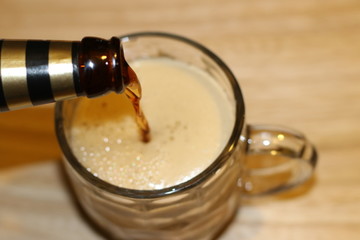 Black beer is pouring into glass cup