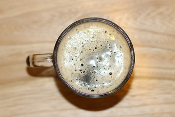 Foamy black beer is poured into glass cup