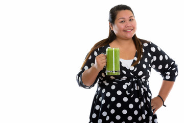 Studio shot of young happy fat Asian woman smiling while holding