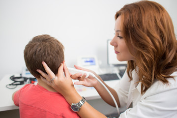 Young boy at medical examination or checkup in otolaryngologist's office. 