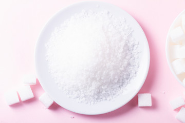 Fototapeta na wymiar Sugar in crystaline sand, flat lay on pink background