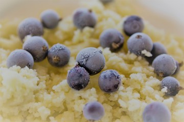 Breakfast porridge couscous with frozen blackcurrant berries closeup