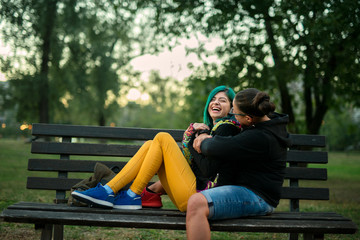 Two young girls sitting in the park, having fun, taking photos and enjoying time spent together. Couple concept.