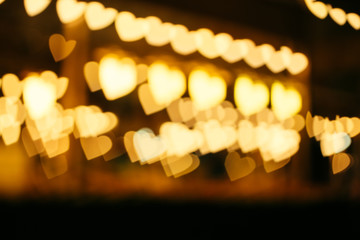 The blurred bokeh of the golden heart shape from the line of light in the night at the street store