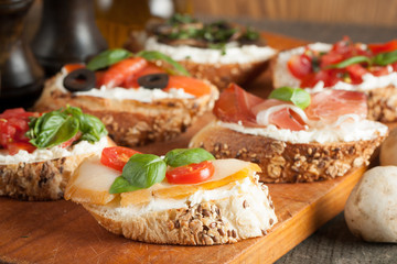 Italian tomato and cheese bruschetta. Tapas, antipasti with chopped vegetables, herbs and oil on grilled ciabatta and baguette bread.
