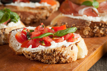 Italian tomato and cheese bruschetta. Tapas, antipasti with chopped vegetables, herbs and oil on grilled ciabatta and baguette bread.