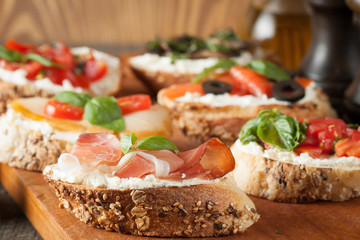 Italian tomato and cheese bruschetta. Tapas, antipasti with chopped vegetables, herbs and oil on grilled ciabatta and baguette bread.