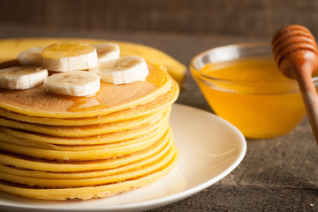 Tasty pancakes with blackberries, banana, raspberries, eggs, honey and maple syrup on wooden background. Morning breakfast concept.
